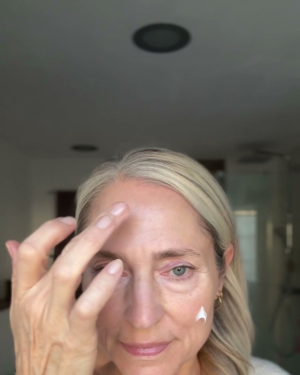 Frau um die 50 tupft Creme unter das Auge